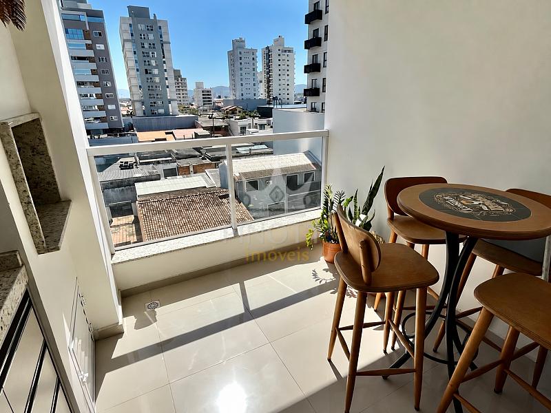 Sacada envidra�ada com mesa, cadeiras e vista urbana no apartamento em S�o Jo�o, Itaja�.