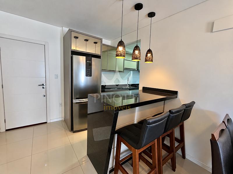Cozinha integrada � �rea de refei��es, com bancada e banquetas no Edif�cio Attualita, em Itaja�.