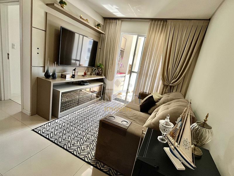 Sala de estar com tapete, sof� e painel de televis�o no apartamento do Edif�cio Attualita, em Itaja�.