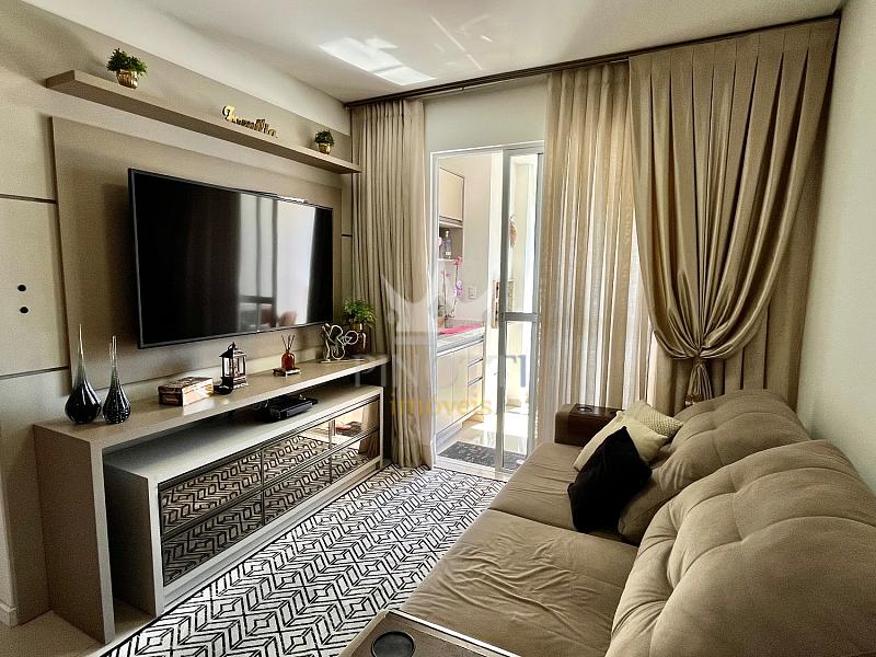 Sala de estar com sof�, painel de televis�o e cortinas no apartamento em S�o Jo�o, Itaja�.
