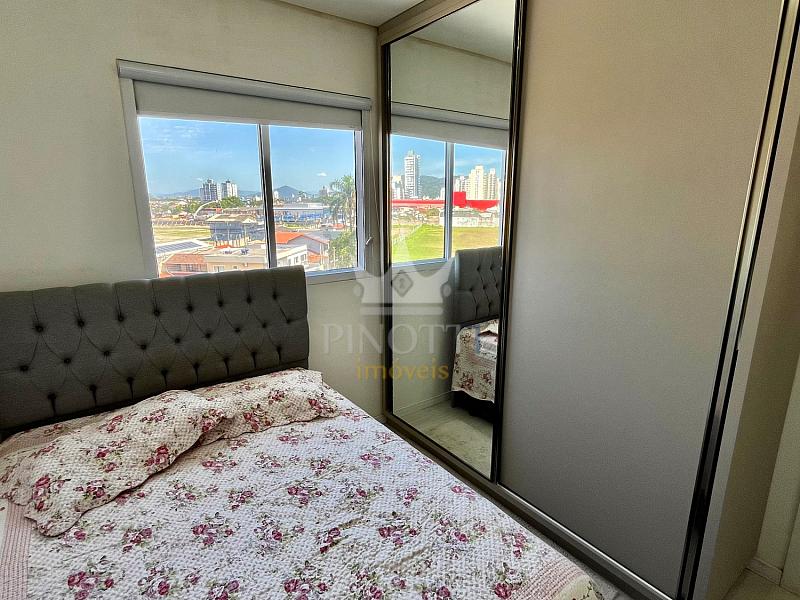 Dormit�rio com cama, janela e arm�rio com portas espelhadas no Edif�cio Attualita, em Itaja�.
